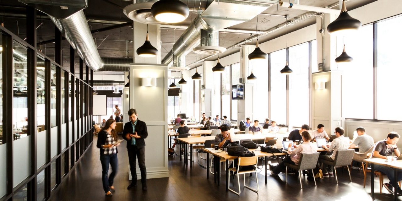 orang-orang sedang bekerja dalam coworking space dengan partisi kaca